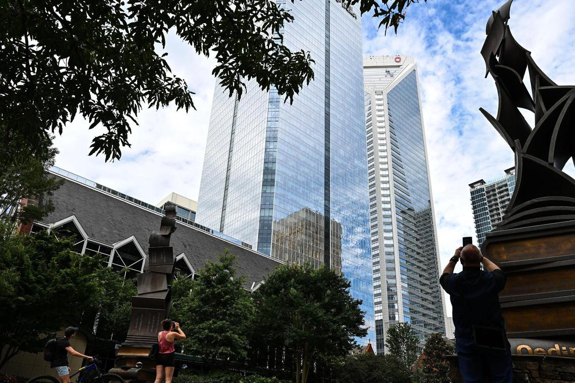 Pedestrians look on as letters are placed onto the top of the Wells Fargo building in uptown, Sunday, June 15, 2025, in Charlotte, N.C.