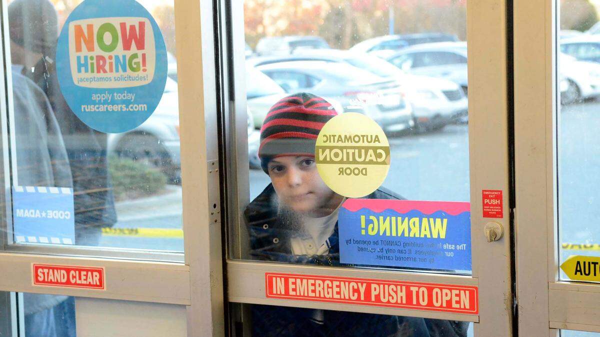 A young shopper peers through the front entrance at the Toys R Us while waiting in line for the store to open at 5PM on Thanksgiving Day in Pineville, Nov. 28, 2013.