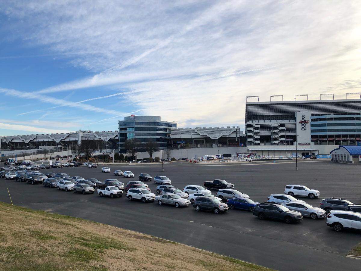 Lines of cars curve through a parking lot at Charlotte Motor Speedway as people prepare to be vaccinated for the COVID-19 virus.