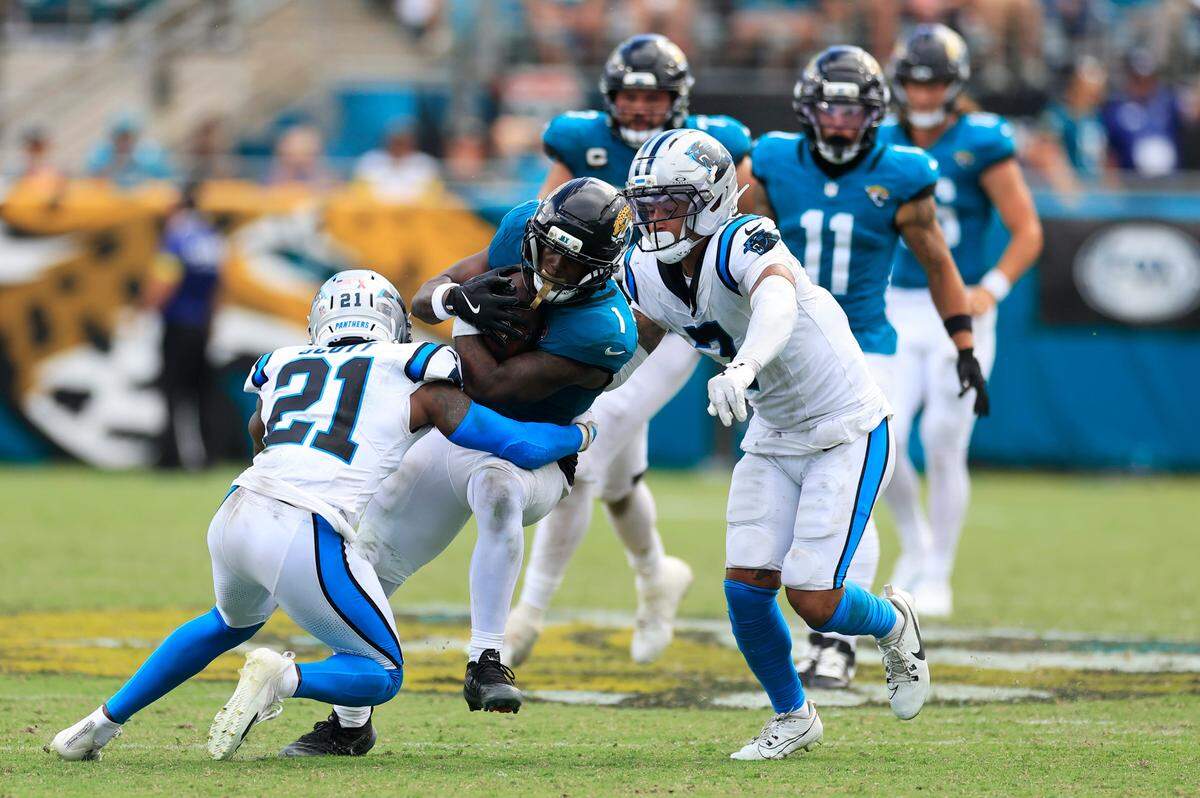 Jacksonville Jaguars running back Travis Etienne Jr. (1), center, rushes for yards against Carolina Panthers safety Nick Scott (21), left, and safety Tre'von Moehrig (7) during the fourth quarter of an NFL football matchup at EverBank Stadium, Sunday, Sept. 7, 2025 in Jacksonville, Fla. The Jaguars defeated the Panthers 26-10. [Corey Perrine/Florida Times-Union]