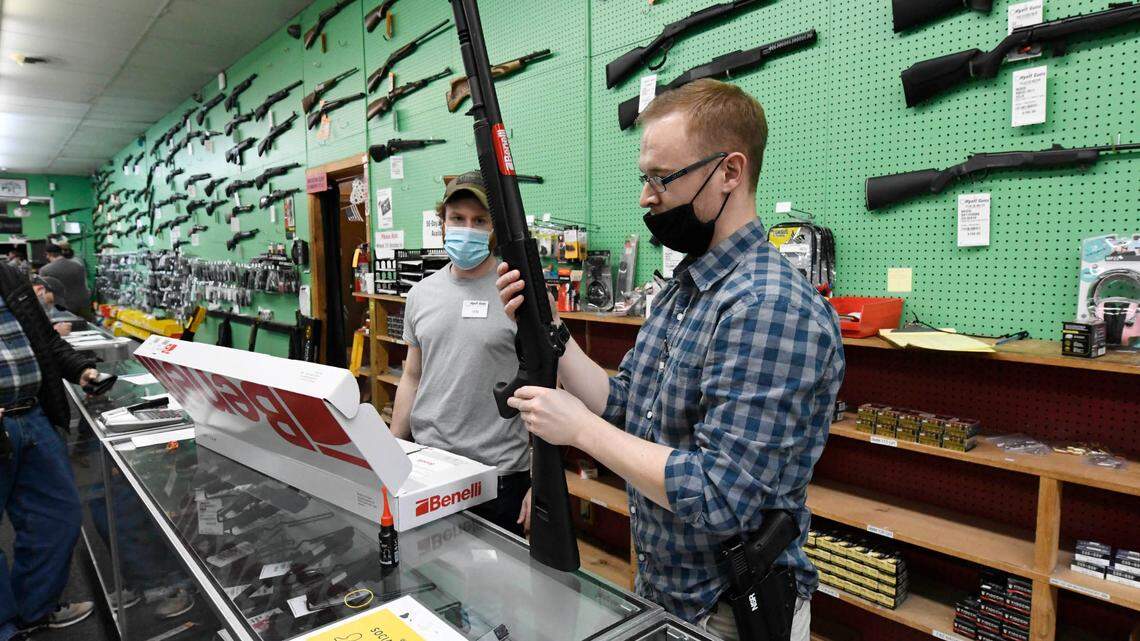 Salesmen Ted Shore, right, and Ian Mahathey assemble a shotgun for a customer at Hyatt Gun Shop in Charlotte on Jan. 20, 2021. Store owner Larry Hyatt said the store was seeing unprecedented demand for guns and ammunition.