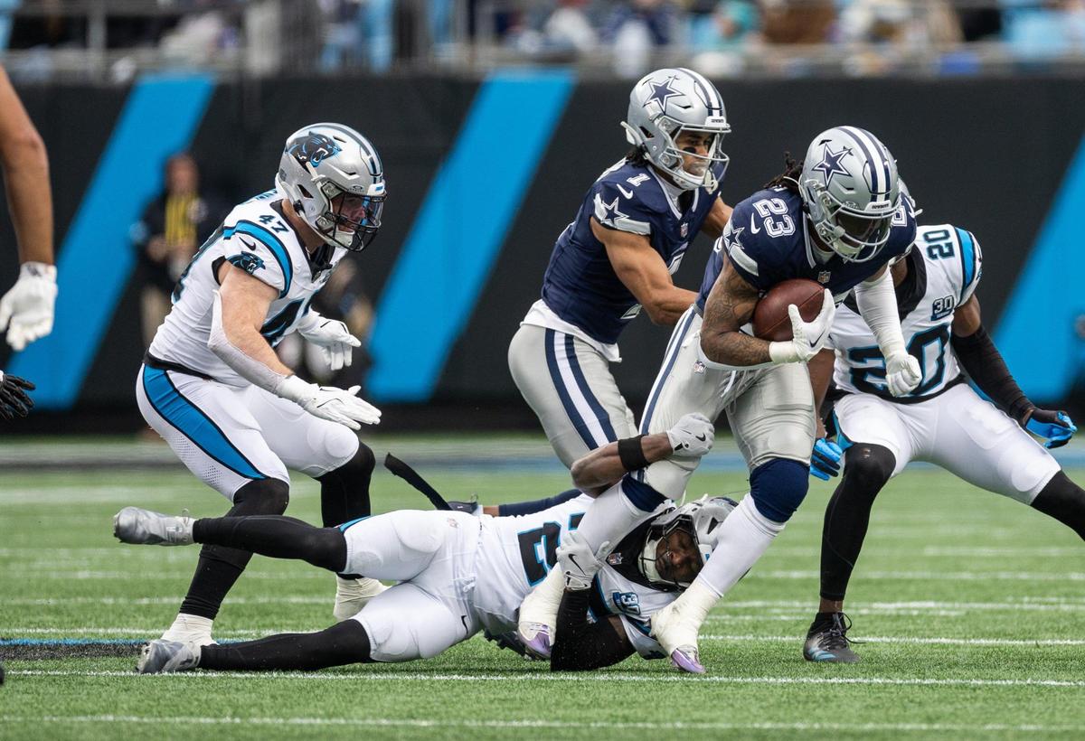 Dallas Cowboys running back Rico Dowdle, right, is tackled by Carolina Panthers safety Xavier Woods at the Bank of America Stadium in Charlotte, N.C., on Sunday, December 15, 2024.