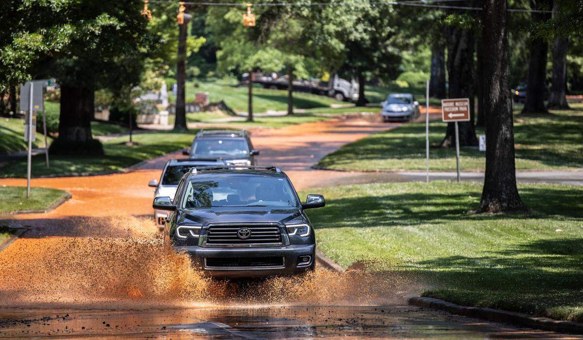 Cars drive down Queens Road West where a water main broke in Charlotte, N.C., on Friday, May 21, 2021.