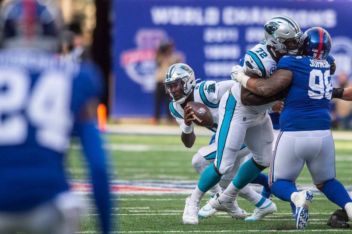 Panthers tackle Taylor Moton, center, holds off Giants defensive lineman Austin Johnson as Panthers quarterback PJ Walker, back left, scrambles on a quarterback keeper during the game against the Giants at MetLife Stadium on Sunday, October 24, 2021 in Rutherford, NJ. The Panthers, who did not score a single touchdown, lost to the Giants, 24-3. This is the Panthers fourth straight loss after a 3-0 start to the season.