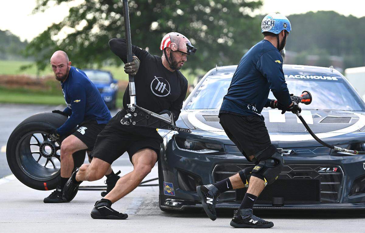 NASCAR driver Ross Chastain’s Trackhouse Racing pit crew members (L-R) Matt Simmons, Shane Wilson and Michael Roberts race around the car during pit practice on Tuesday, June 11, 2024.
