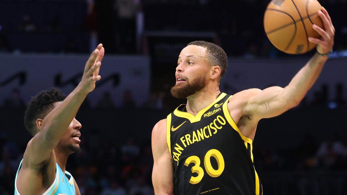 Golden State Warriors guard Steph Curry, right, passes the ball over Charlotte Hornets forward Brandon Miller, left, during action at Spectrum Center in Charlotte, NC on Friday, March 29, 2024. The Warriors defeated the Hornets 115-97.