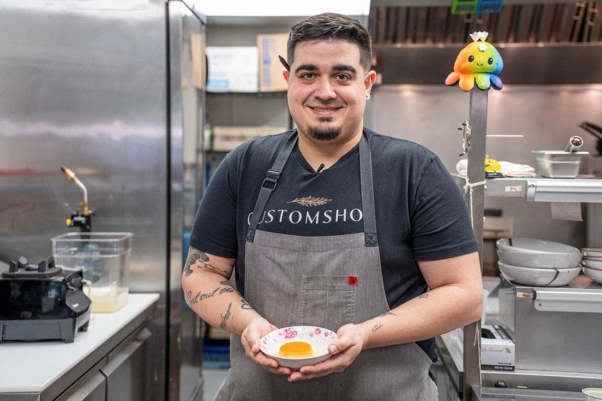 Chef Andres Raifer holds a flan — made with an adaptation of his mother’s recipe — that is served at Customshop.
