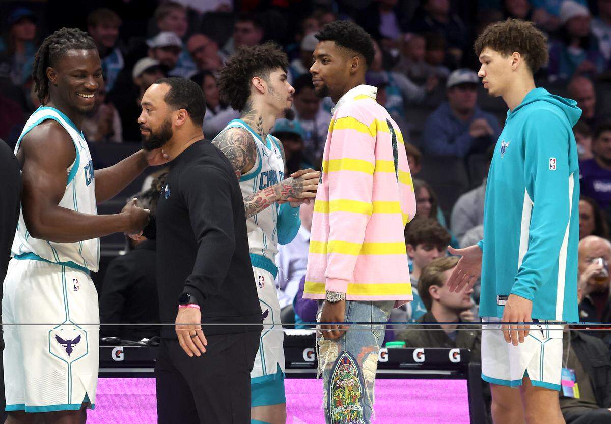 Injured Charlotte Hornets forward Brandon Miller, center, shakes hands with his teammates as they prepare to play the Orlando Magic at Spectrum Center in Charlotte, NC on Thursday, October 30, 2025. The Magic defeated the Hornets 123-107.