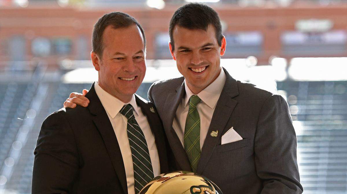 Charlotte 49ers Director of Athletics Mike Hill, left, and football coach Will Healy stop for a portrait with a helmet during Healy’s introductory news conference in 2018. Healy’s contract was extended through 2026 on Tuesday.