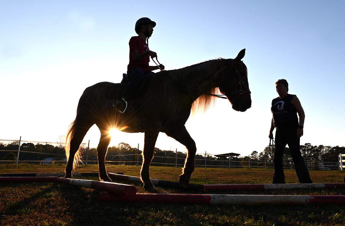 Chancellor Lee Adams, center, rides Roanie, a 22-year-old American quarter horse as Dory Pell, right, the program director at Victory Farm watches on Friday, November 8, 2024. Victory Farm is a therapeutic riding center in Gastonia.