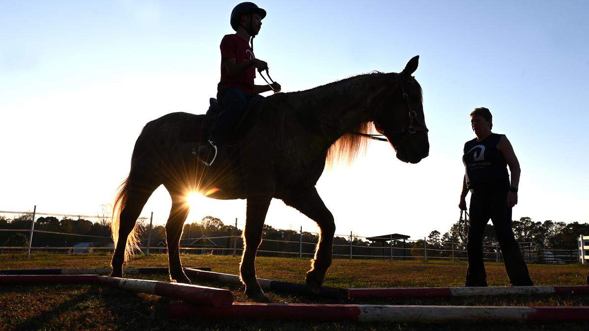 Chancellor Lee Adams, center, rides Roanie, a 22-year-old American quarter horse as Dory Pell, right, the program director at Victory Farm watches on Friday, November 8, 2024. Victory Farm is a therapeutic riding center in Gastonia.