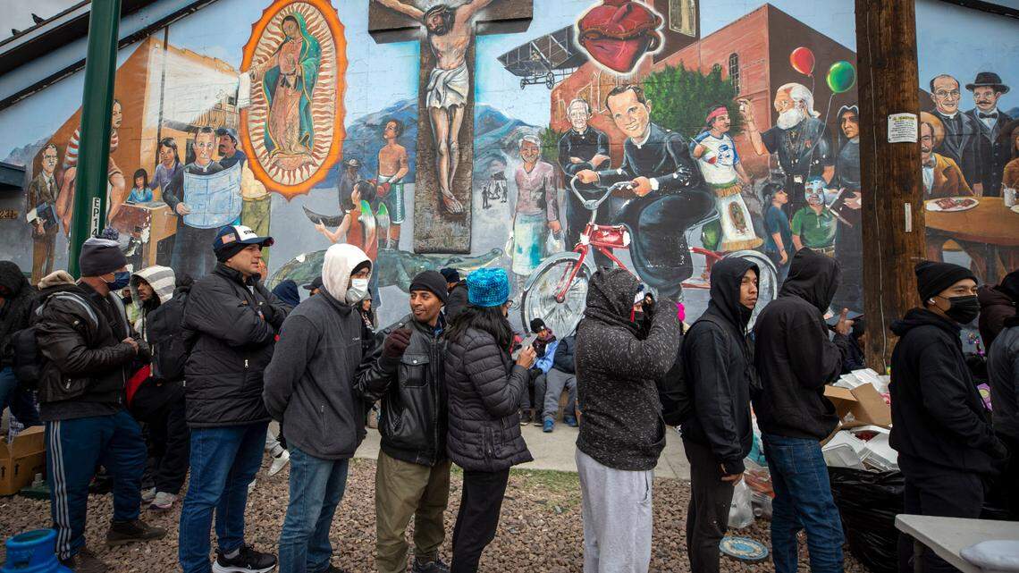 Migrants form a line to receive warm food donated by residents in downtown El Paso, Texas, Sunday, Dec. 18, 2022. Texas border cities have seen a surge of as many as 5,000 new migrants a day across the U.S.-Mexico border in recent weeks.