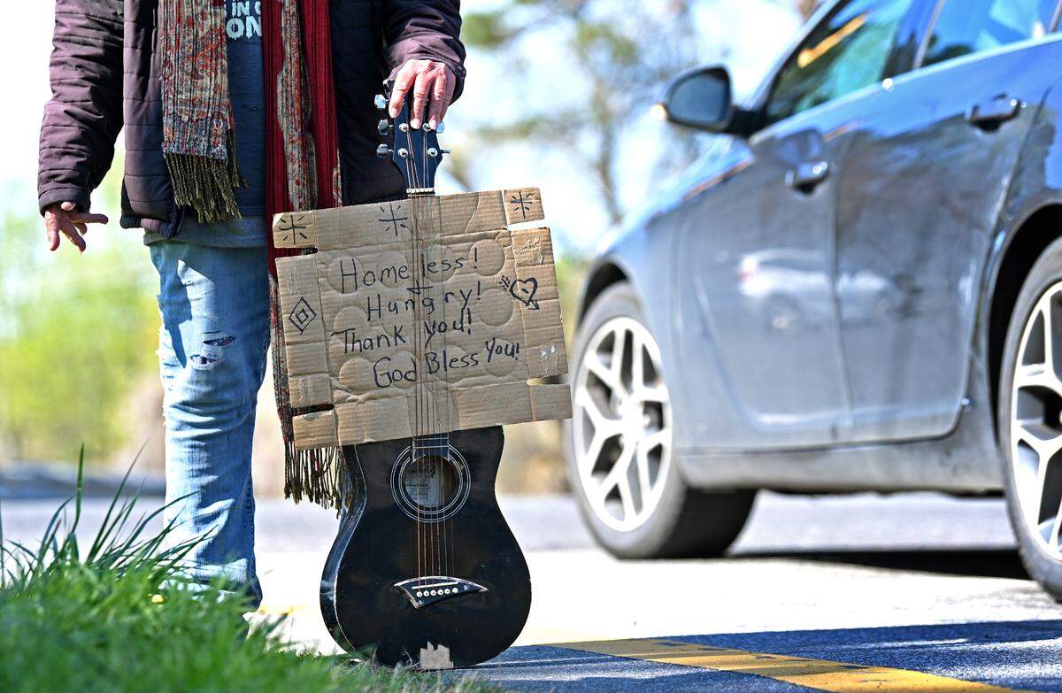 A woman who identified herself as Belinda waits with her guitar at the foot of an exit ramp off I-77 South, hoping motorists will hand her some money.