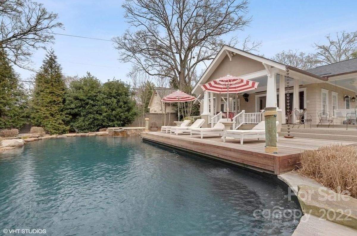 Retractable glass doors at the Queens Road West home open to a veranda that overlooks a resort-style salt water pool, with a hot tub and an attached fresh-water koi pond.