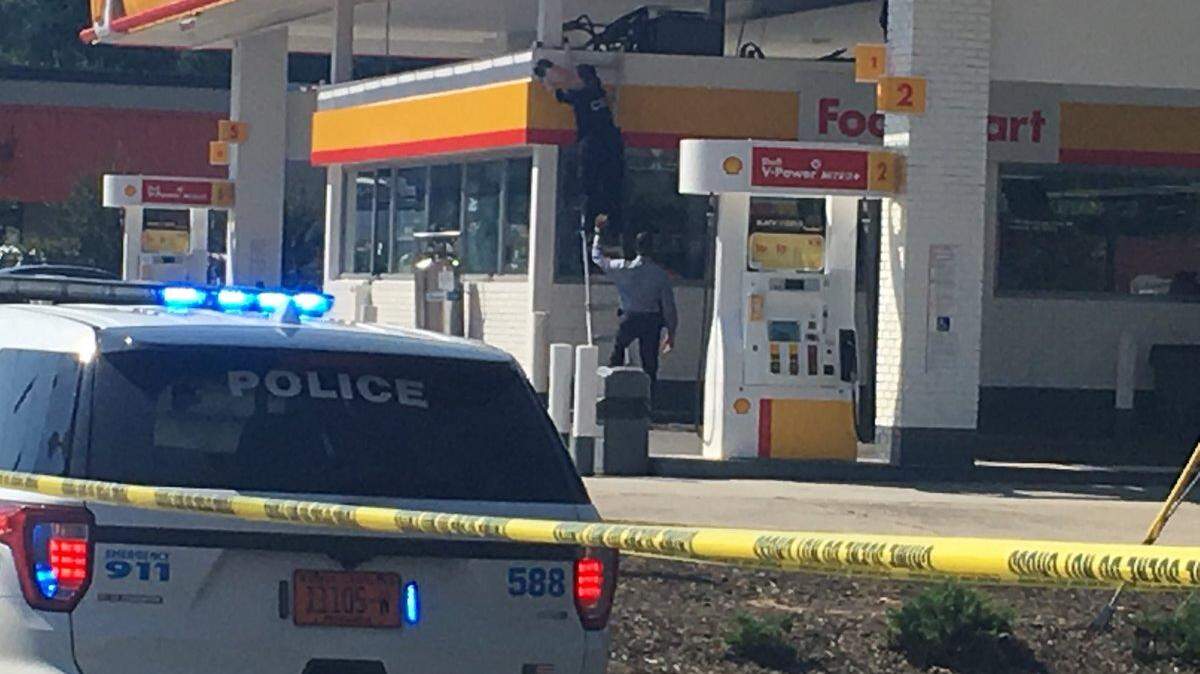 A Charlotte-Mecklenburg Police crime scene investigator climbs a ladder while examining the scene of a shooting on West Sugar Creek Road Wednesday.
