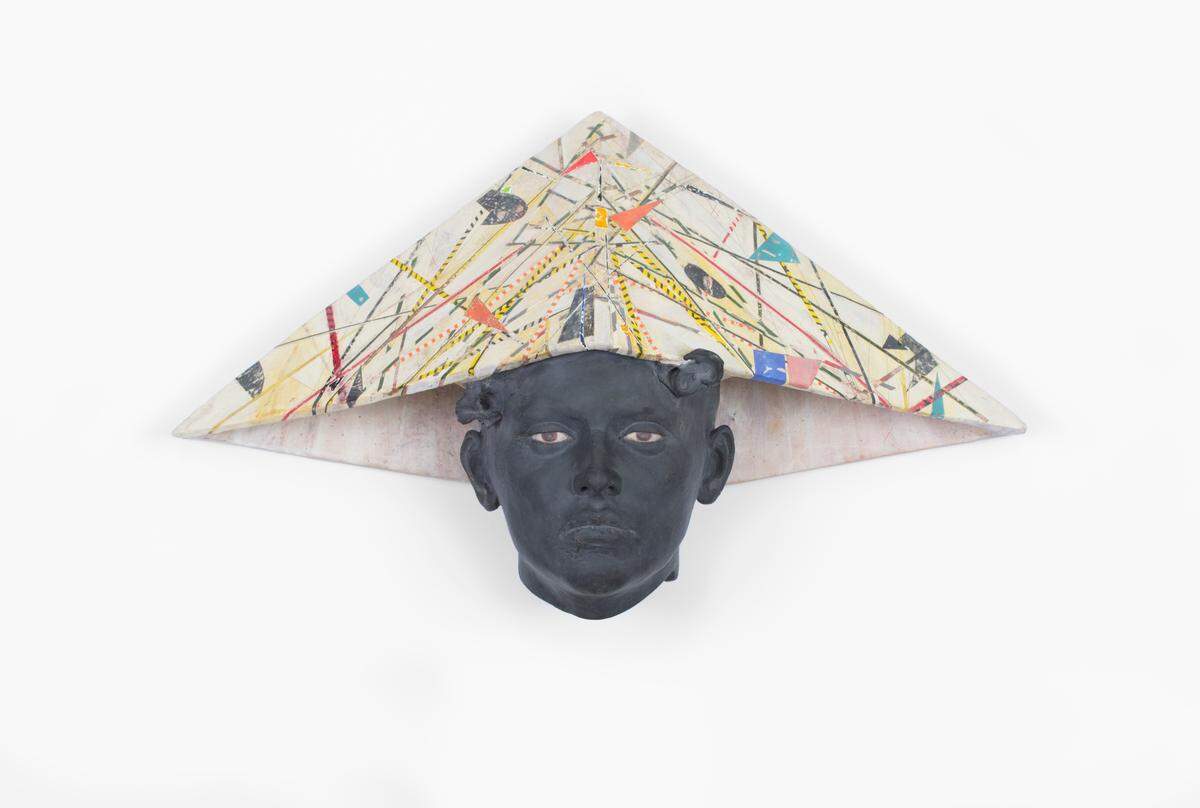 This ceramic work by Cristina Córdova features a black face topped with a brightly patterned triangular headdress in the style of a child’s newspaper hat. The patterning of the headdress is colorful and active in contrast to the dark, still face, resulting in a work that is equal parts static and dynamic.