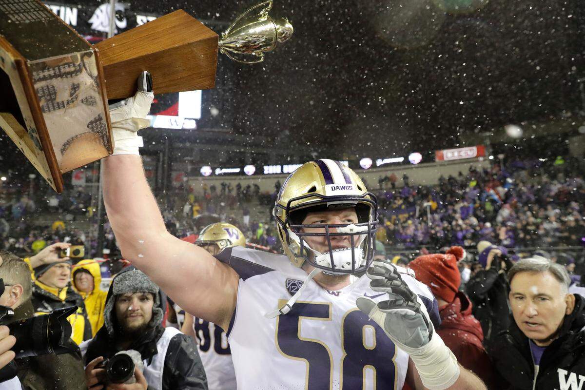 Washington offensive lineman Kaleb McGary holds up the Apple Cup trophy after Washington defeated Washington State 28-15 in an NCAA college football game, Friday, Nov. 23, 2018, in Pullman, Wash. (AP Photo/Ted S. Warren)