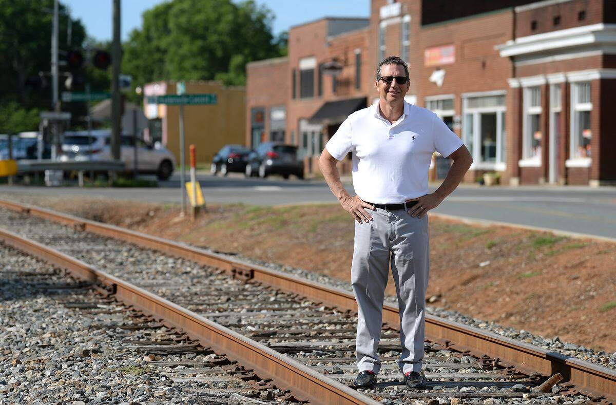 Huntersville Mayor John Aneralla stands on the railroad track traveling down Main St. in Huntersville on Thursday, July 1, 2021. The track is owned by Norfolk Southern Corp. and they have been an impediment to the Charlotte regions’ goal for a commuter line to Mooresville to center city. Mayor Aneralla is opposed to a proposed one-cent mobility tax.