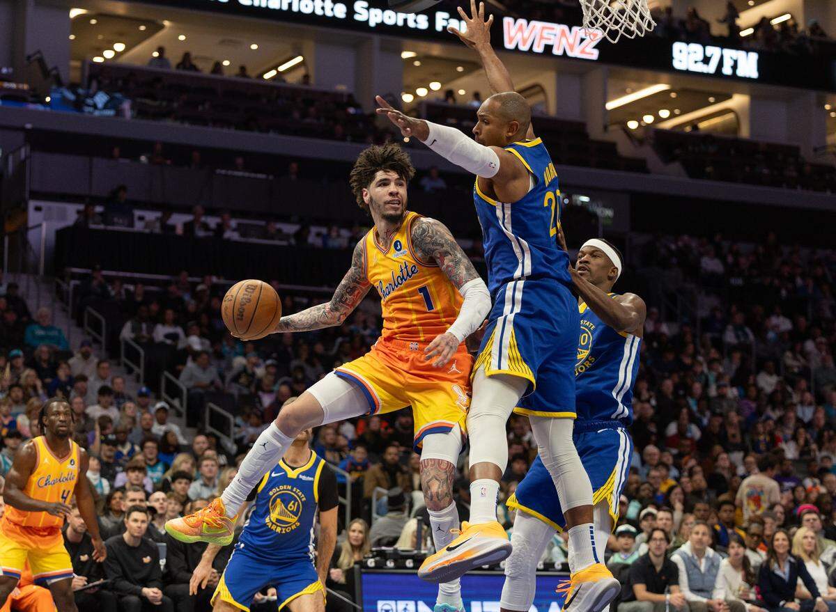 Charlotte Hornets guard Lamelo Ball, left, passes the ball past Golden State Warriors center Al Horford at the Spectrum Center in Charlotte, N.C., on Wednesday, December 31, 2025.