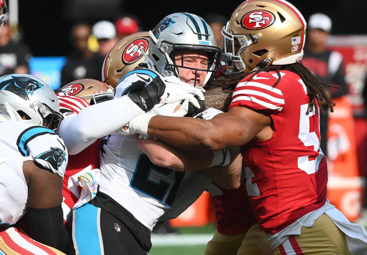 Carolina Panthers running back Christian McCaffrey, center, is wrapped up by San Francisco 49ers linebacker Fred Warner, right, on a run during first quarter action at Bank of America Stadium on Sunday, October 9, 2022.