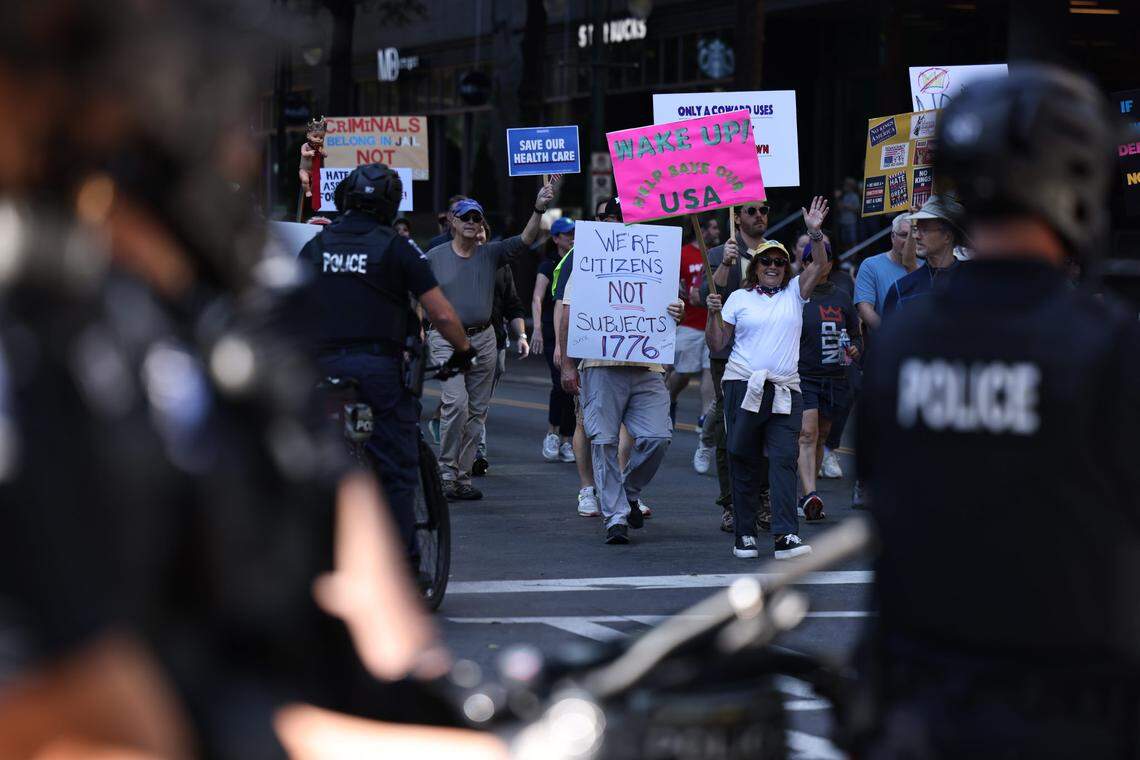 The ‘No Kings’ protest marches through uptown Charlotte on Saturday, Oct. 18, as CMPD officers look on. The rally began at 10 a.m. at First Ward Park before descending onto the streets.