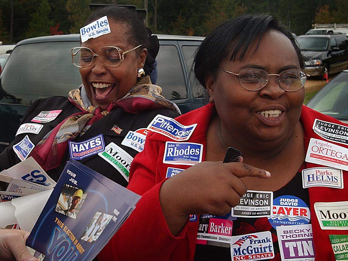 Pauline Simuel, left, and Linda Williams, both of the Optimist Park neighborhood in Charlotte, have some fun with stickers as they go through the line of political candidates at the annual Mallard Creek Barbecue Thursday, Oct. 24, 2002. 