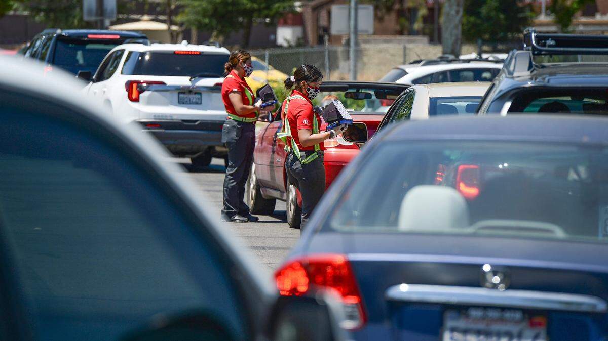Chick-Fil-A employees take orders from customers lined up in the drive-thru line at Chick-Fil-A in Fresno at noon on June 8, 2021.