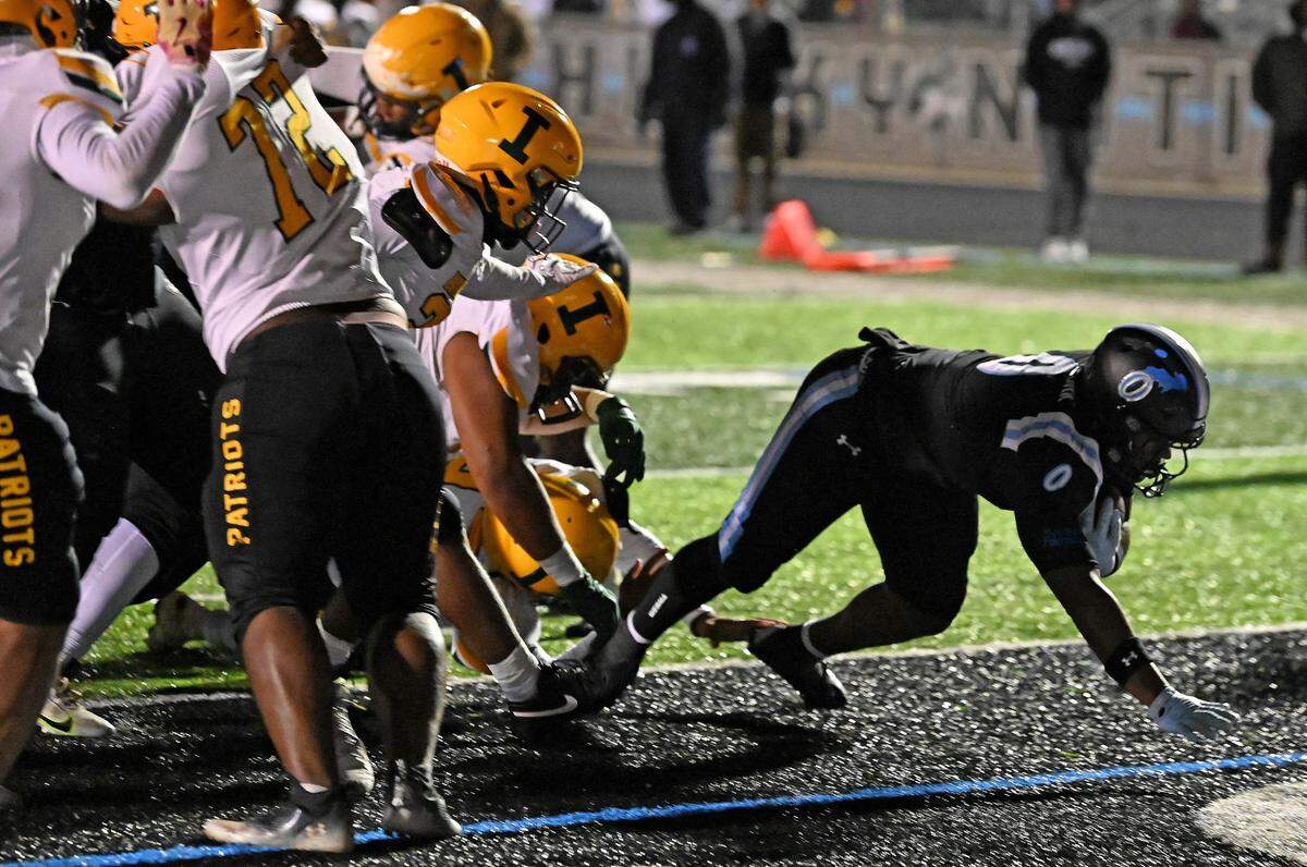 Hough Huskies running back Jamison Funderburk, right, stretches into the end zone for a touchdown as the Independence Patriots defense attempts to tackle him during action on Friday, November 22, 2024.