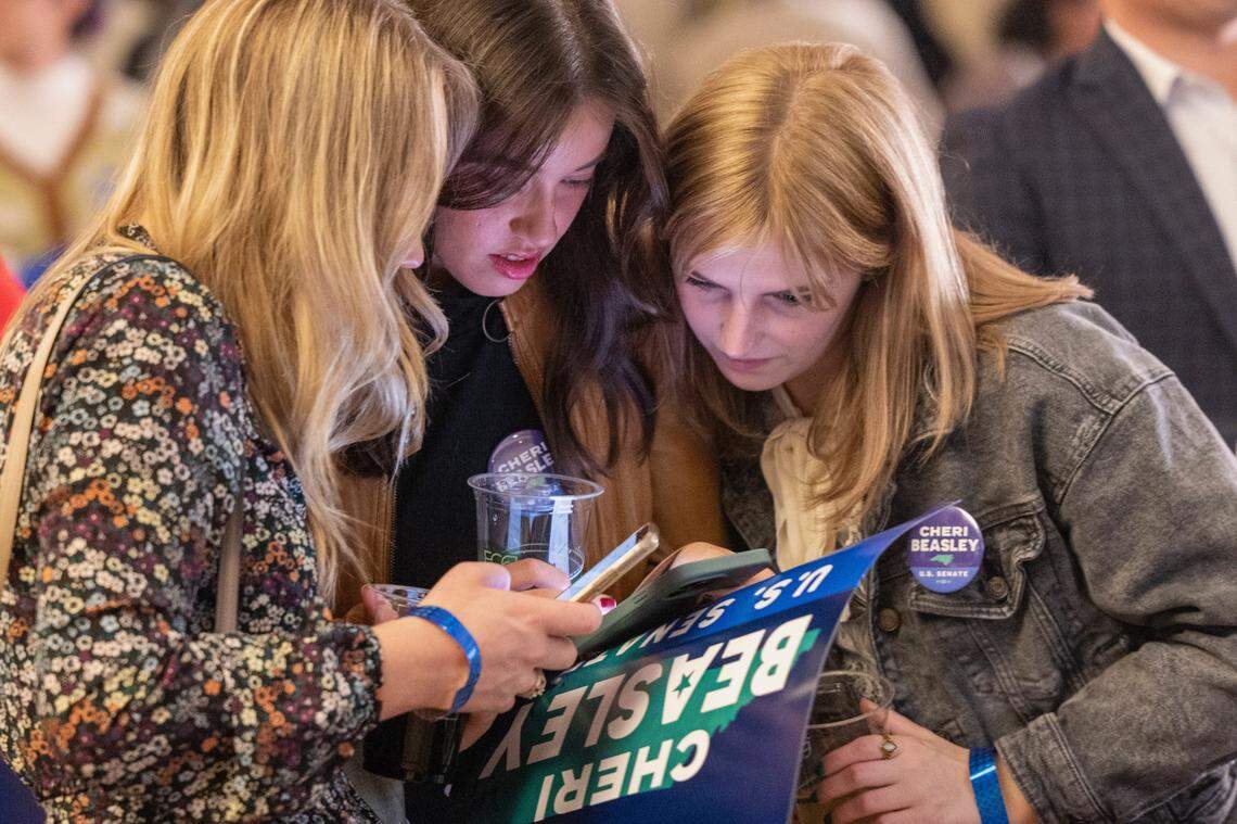Supporters of U.S. Senate Democrat candidate Cheri Beasley from left, Ava Bowman Thomas, Emily Mintz and Haley Hendrick&nbsp;look at early election results during an election watch party Tuesday, Nov 8, 2022 at the Sheraton in downtown Raleigh.