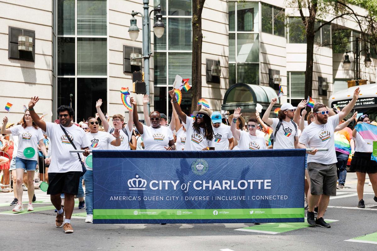 Participants representing the City of Charlotte cheer and wave to the audience. The group was followed by a local Charlotte bus that displayed the text “Ride with Pride” instead of its usual bus routes during the Charlotte Pride Festival & Parade on Sunday, Aug. 18, 2024