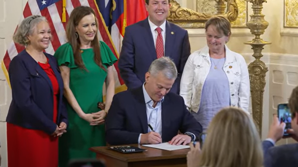 NC Gov. Josh Stein, flanked by Charlotte-area leaders, signs a bill allowing Mecklenburg County to put a sales tax referendum on the ballot to pay for transportation projects.