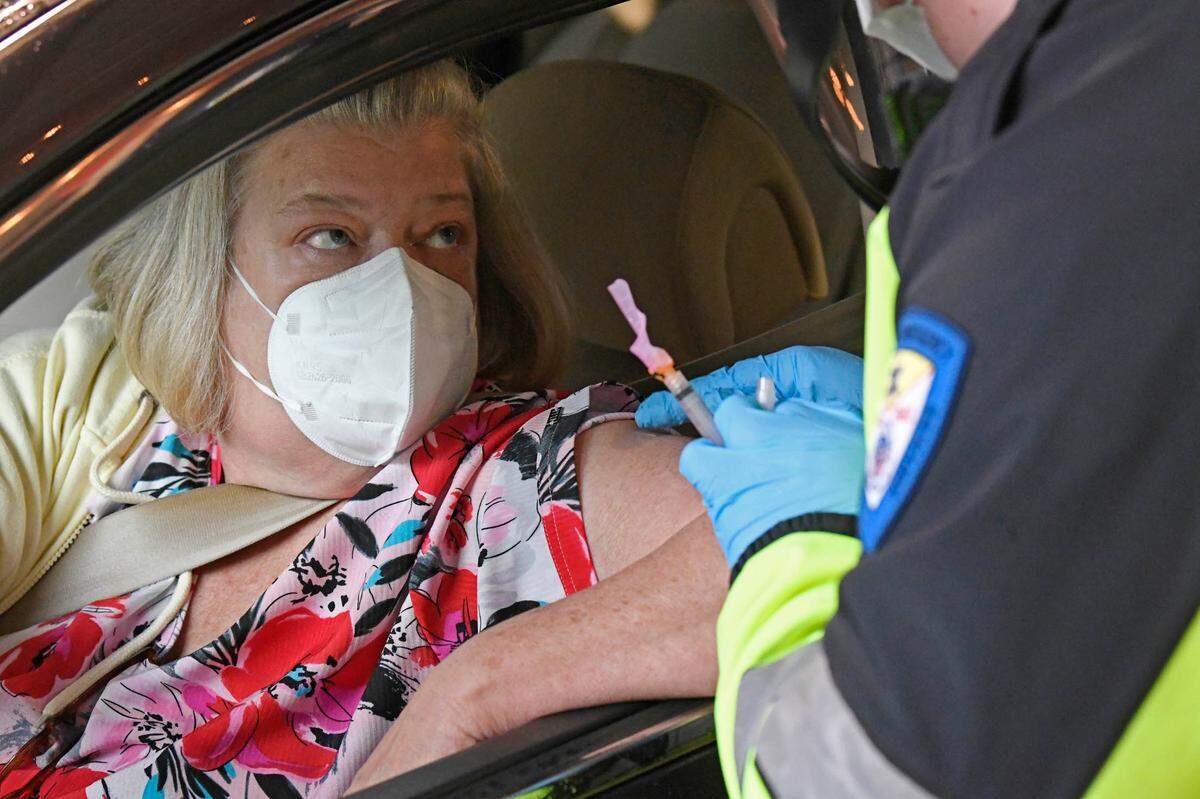 Lisa Bowman watches as she gets a COVID vaccination from a Gaston County Emergency Medical Services (GEMS) medical personnel during Gaston County Department of Health and Human Services sponsored Phase 1B vaccine clinic at the Gastonia Farmer’s Market on Friday, January 8, 2021.