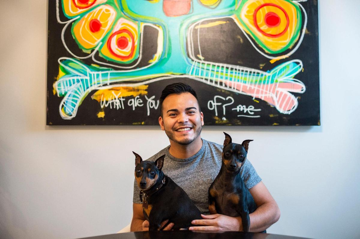 Candelario Saldana with his miniature pinschers, Zelda, left, and Dante, in his home on Oct. 8, 2021 in Charlotte.  “National Coming Out Day for me is a day to not only celebrate, but to remind us of the work that still needs to be done,” Saldana said. 