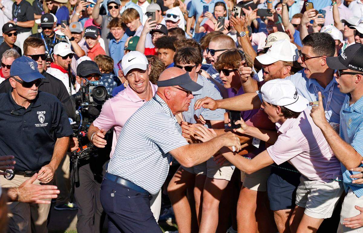 Rory McIlroy, center, smiles as he runs up a hill off the 18th green to go sign his golf card after winning the Wells Fargo Championship on Sunday, May 12, 2024 at Quail Hollow Club in Charlotte, NC. McIlroy won at -17.