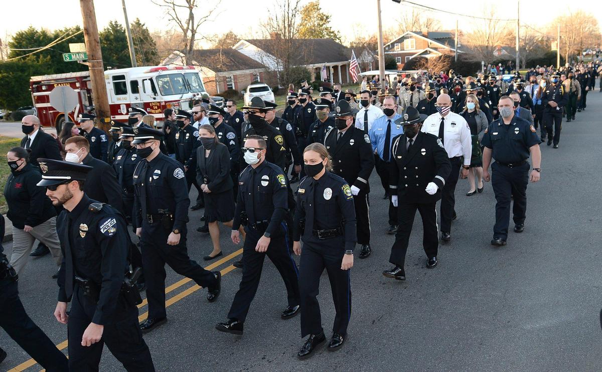 A procession of police officers walk down Main St. in Faith, NC for the graveside services for fallen Concord police officer Jason Shuping on Tuesday, December 22, 2020. Officer Shuping was killed in the line of duty last week. The officer was responding to an attempted carjacking outside a fast food restaurant near Concord Mills.