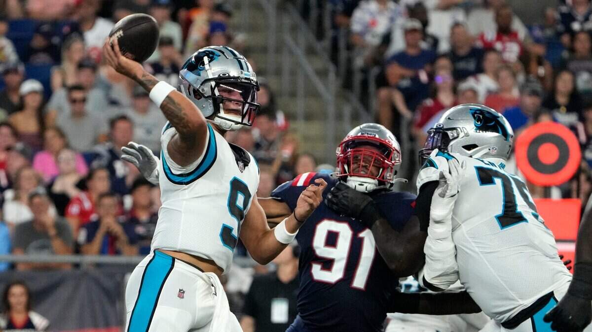 Carolina Panthers quarterback Matt Corral (9) passes under pressure from New England Patriots defensive end Deatrich Wise Jr. (91) during the first half of a preseason NFL football game Friday, Aug. 19, 2022, in Foxborough, Mass. Corral would later leave the game with a foot injury.