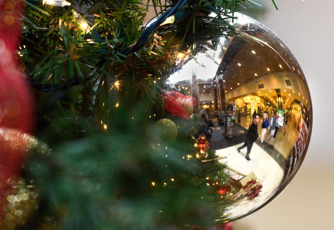 Shoppers are reflected in a Christmas ornament hanging from the tree at SouthPark Mall on thursday November 21, 2013. SouthPark Mall, like others across the Charlotte area, are preparing for the Christmas shopping rush. Many stores opening on Thanksgiving but some are sticking with the more traditional Black Friday kick off of the season. SouthPark already has its Christmas tree in place and Santa Claus stationed at its base to make holiday photos with the children. jsimmons@charlotteobserver.com