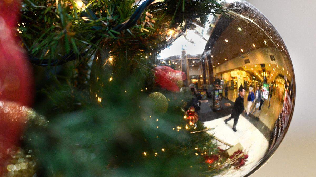 Shoppers are reflected in a Christmas ornament hanging from the tree at SouthPark Mall on thursday November 21, 2013.
 SouthPark Mall, like others across the Charlotte area, are preparing for the Christmas shopping rush. Many stores opening on Thanksgiving but some are sticking with the more traditional Black Friday kick off of the season. SouthPark already has its Christmas tree in place and Santa Claus stationed at its base to make holiday photos with the children. jsimmons@charlotteobserver.com