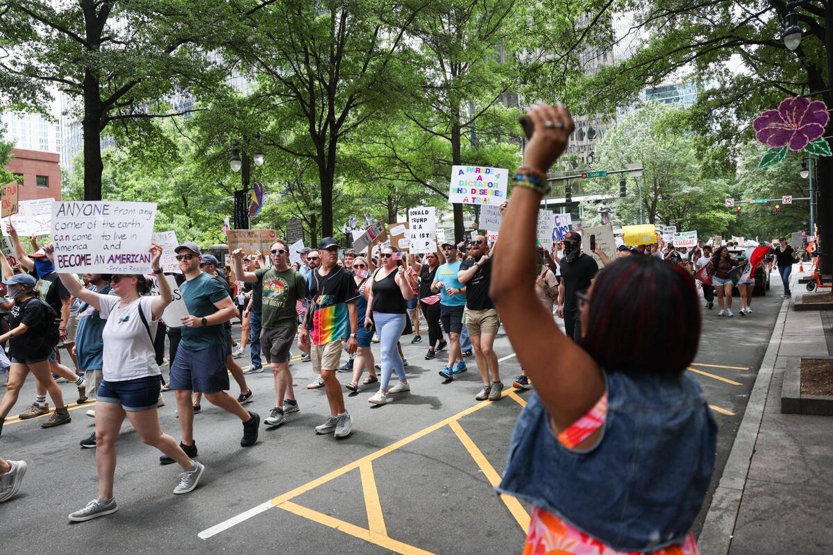 Christy Bohannonb raises her fist to cheer on protesters of the No Kings protest as they march down Tryon Street, heading back to First Ward Park in Charlotte Saturday, June 14, 2025.