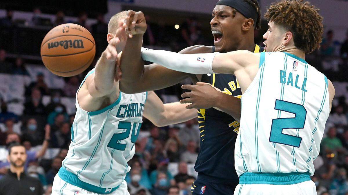 Charlotte Hornets center Mason Plumlee, left and guard LaMelo Ball, right, knock the ball away from Indiana Pacers center Myles Turner, center, during second quarter action at Spectrum Center in Charlotte, NC on Wednesday, October 20, 2021.