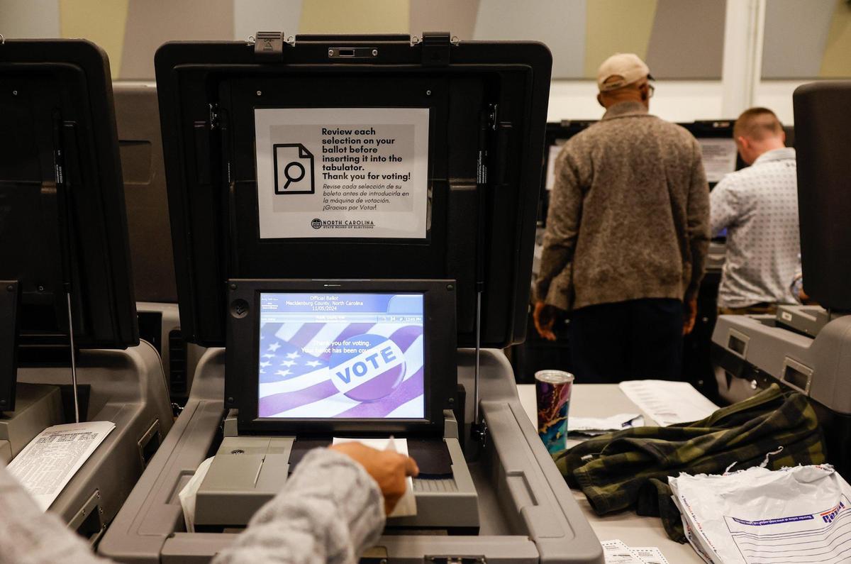 Volunteers feed ballots into machines as Mecklenburg officials hold a recount.