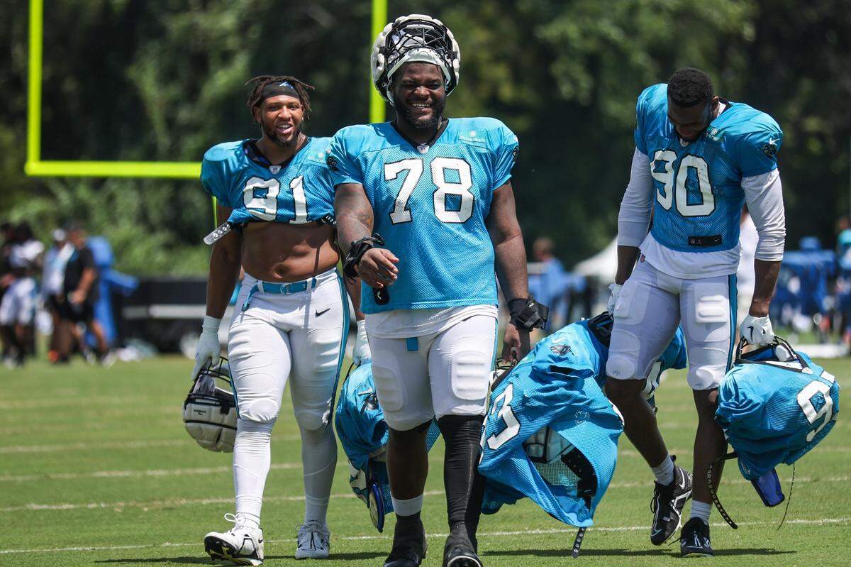 Panthers rookie defensive linemen Drew Jordan, left, Marquand McCall, center, and Amare Barno continue a training camp tradition of rookies carrying the pads and jerseys of veteran players back to the locker room after practice at Wofford College on Tuesday, August 9, 2022 in Spartanburg, SC.