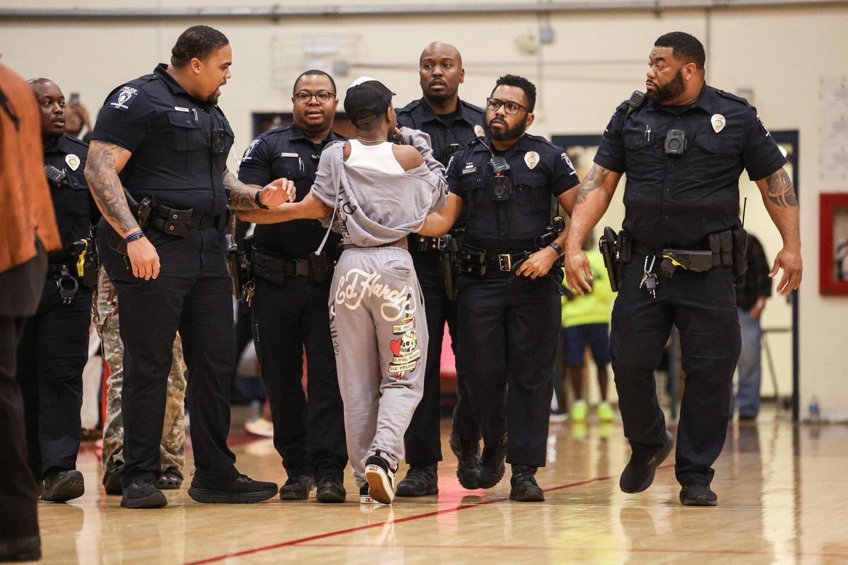 A person is escorted out of the gym by CMPD officers after a fight broke out in the bleachers during the first quarter of the Palisades versus Olympic boy’s basketball game at Olympic High School in Charlotte, NC on Tuesday, February 4, 2025.