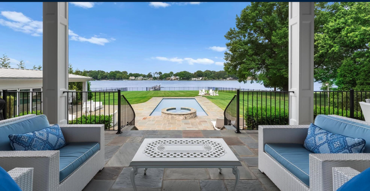 The mansion terrace looks out to a large pool and to the lake.
