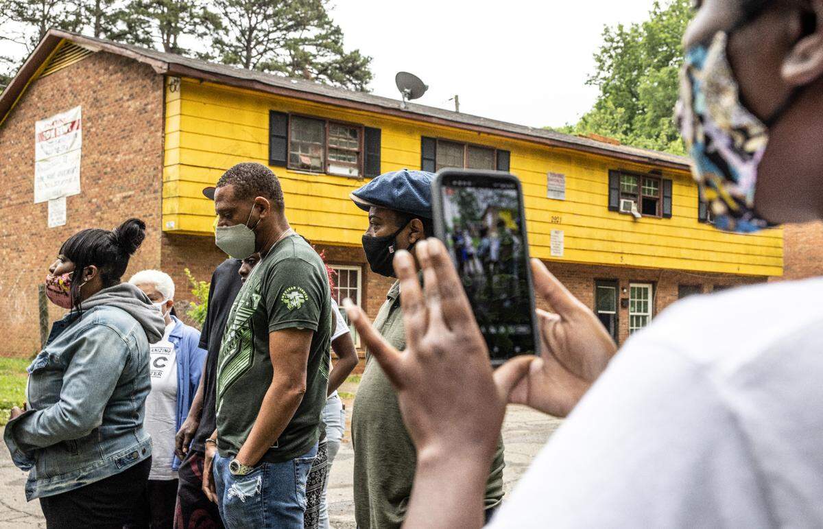 Che Farmer, left, speaks to the media at Woodcrest Apartments in Charlotte, N.C., on Monday, May 3, 2021.