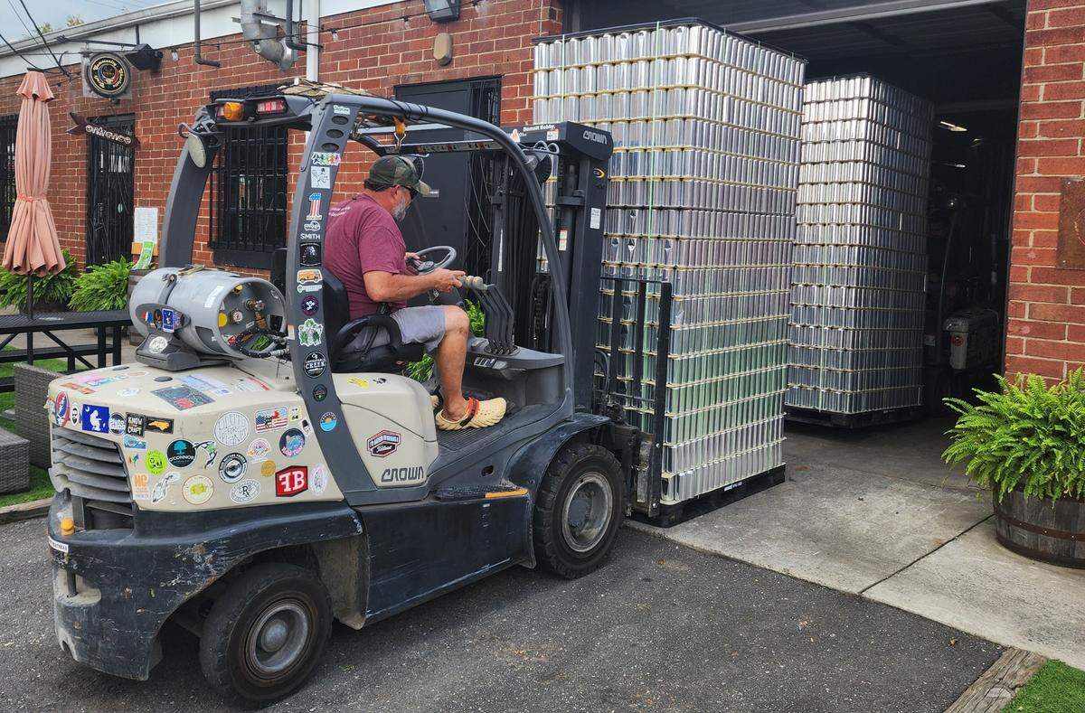 Triple C owner Chris Harker loads up cans filled with water at the brewery. The water will go to help victims of Hurricane Helene.