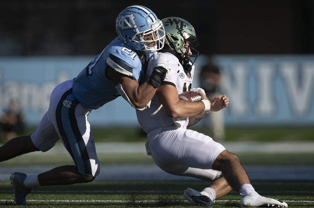 Wake Forest quarterback Sam Hartman (10) is stopped by North Carolina’s Chazz Surratt (21) after a four yard gain in the fourth quarter at Kenan Stadium on Saturday, November 14, 2020 in Chapel Hill, N.C.