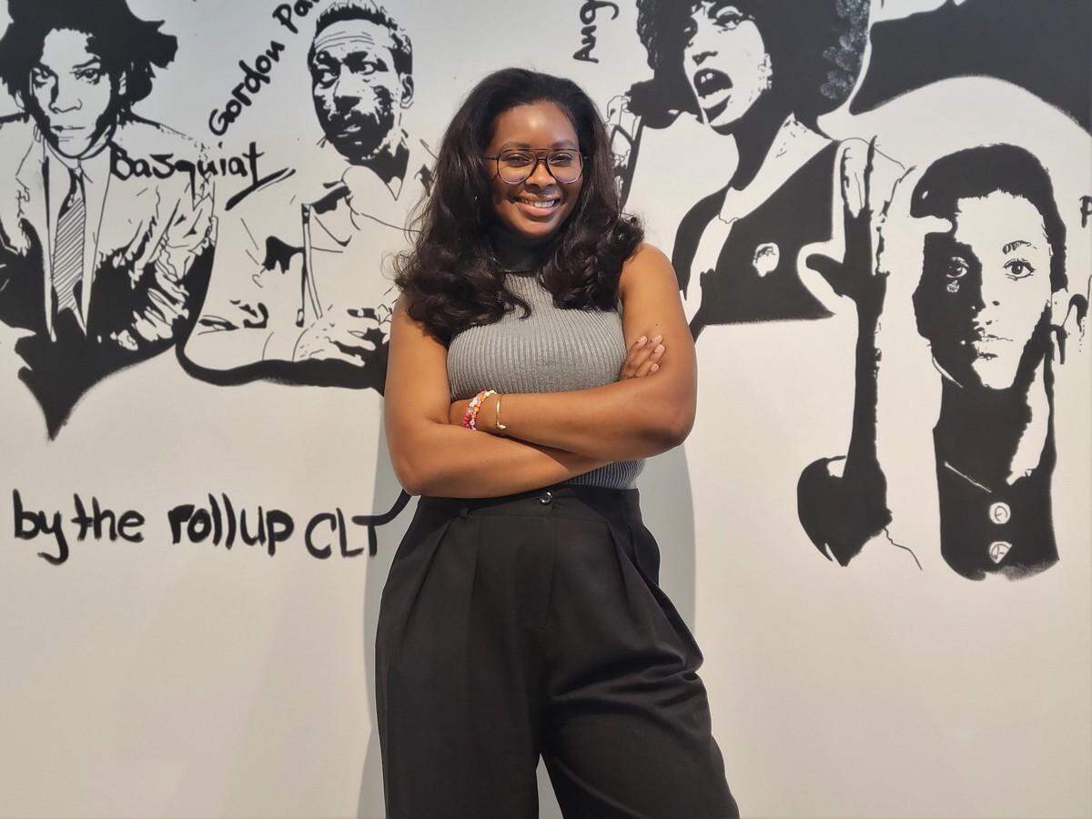 Cheryse Terry stands in front of a mural of Black history makers inside Archive.