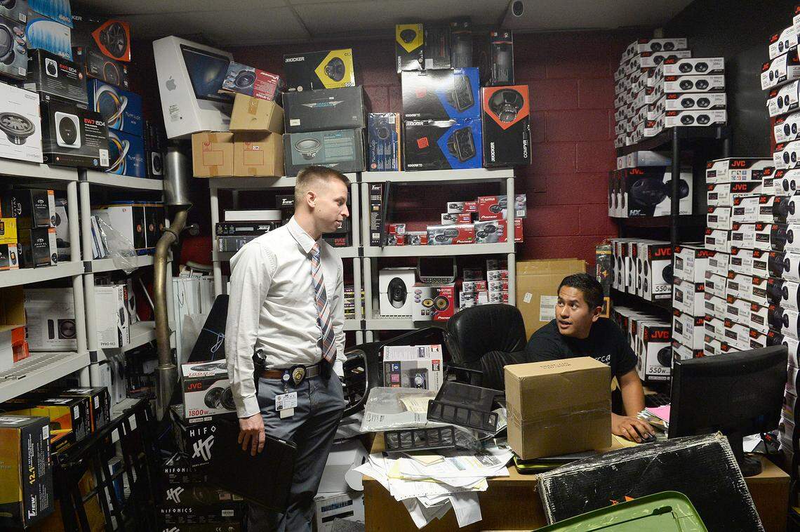 Luis Palomino (right), owner of a car audio shop on Nations Ford Road, helps CMPD Det. Matthew Freeman find the video Freeman needed for an armed robbery investigation. Freeman says he frequently sees subjects he’s arrested more than once still out on the street.