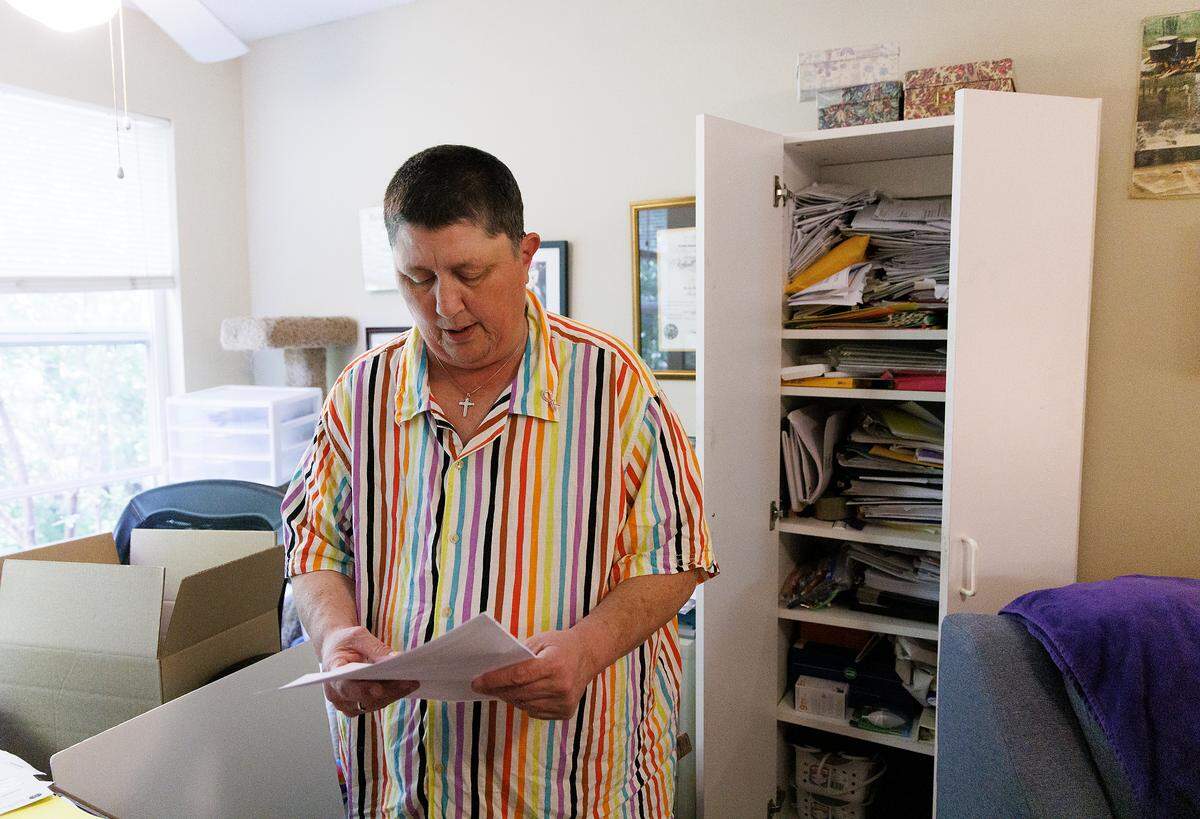 Kerry Holbrook sits near a cabinet in her Durham home where she keeps dozens of medical bills. Sometimes she doesn’t even open them. “I just put them in the closet, because realistically, there’s absolutely no way that I can pay them.”